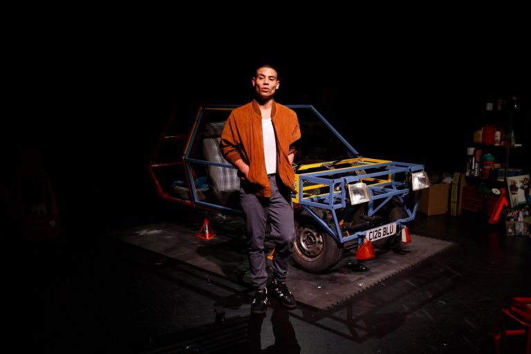 Actor David Judge stands in front of the set for SparkPlug.
